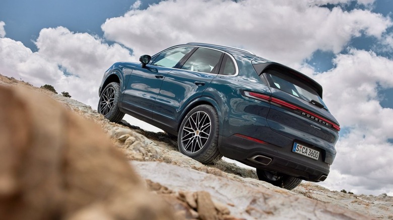 A blue 2026 Porsche Cayenne driving up a steep, rocky incline