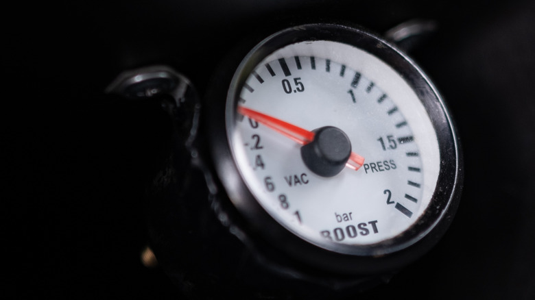 A simple black and white boost and vacuum gauge with an orange needle.