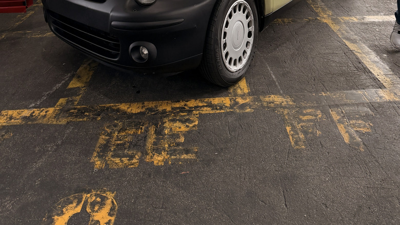 front three quarters shot of a gold Fiat Multipla parked in a building next to a red Ferrari