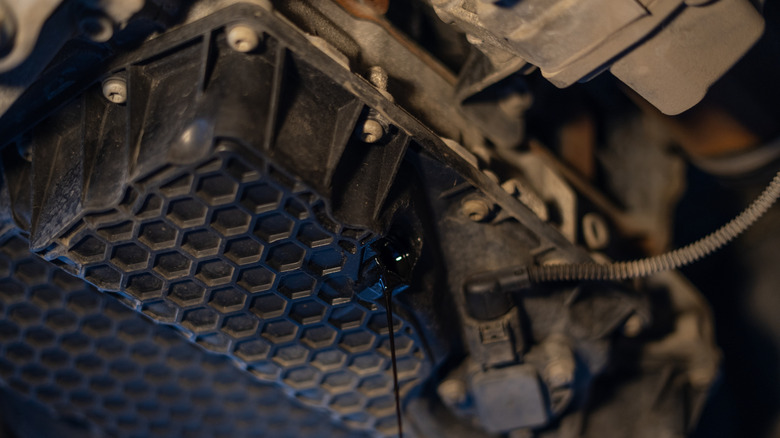 Oil draining from a plastic oil pan under the car's engine