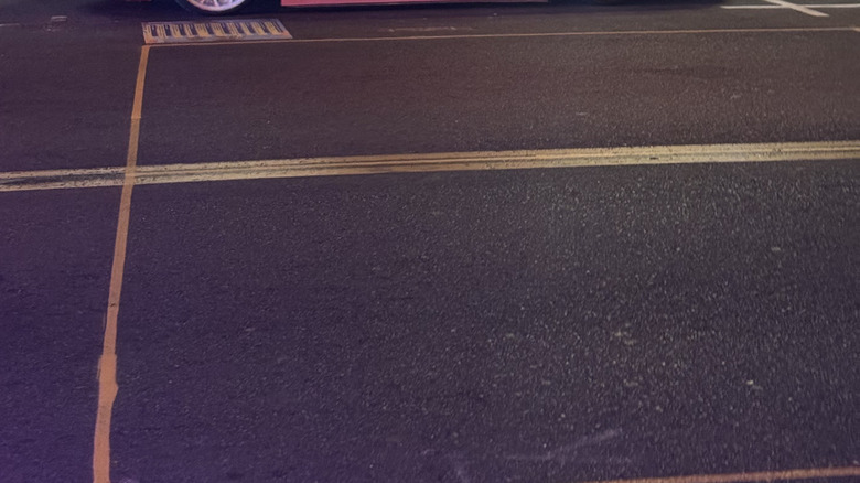 A side view of the slammed pink Toyota Venza with white wheels parked on the street in front of a restaurant