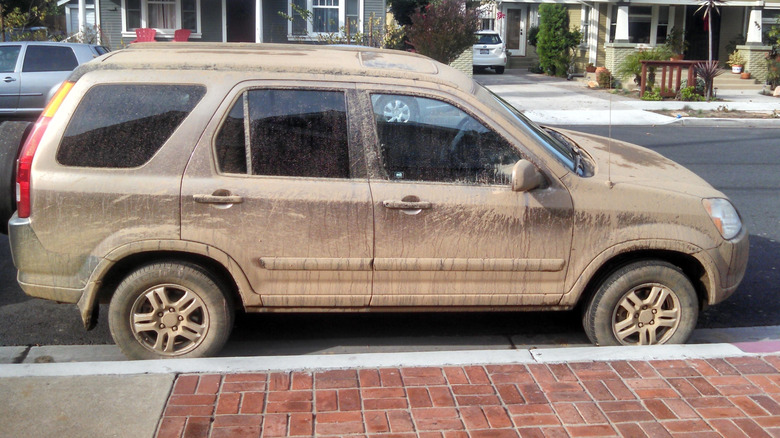 Side view of my brown '03 Honda CR-V covered in mud parked on the street next to bricks