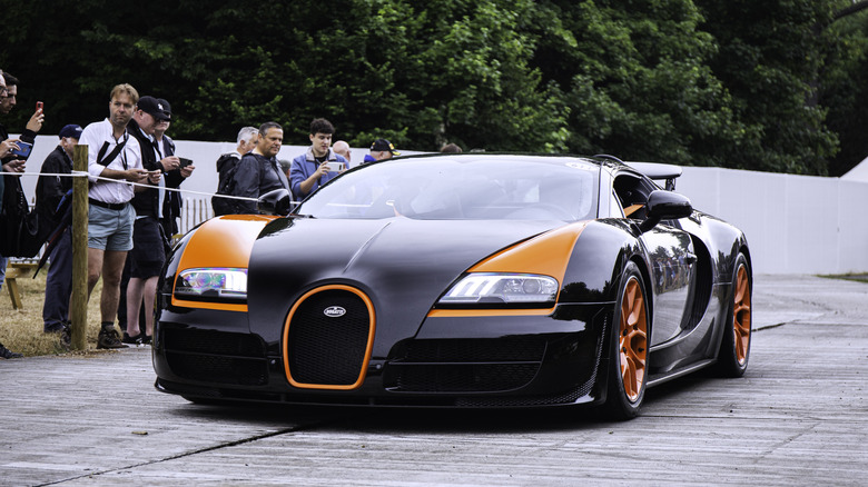 an orange and black Bugatti driving down a causeway at Goodwood Revival Speed