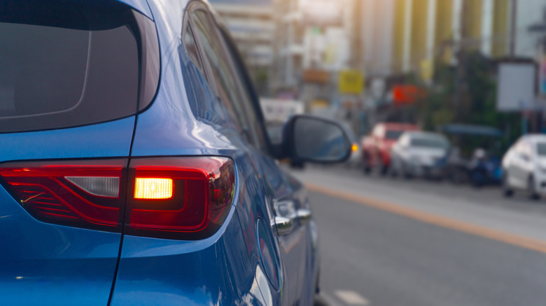 A blue car's brake light as it attempts to enter traffic