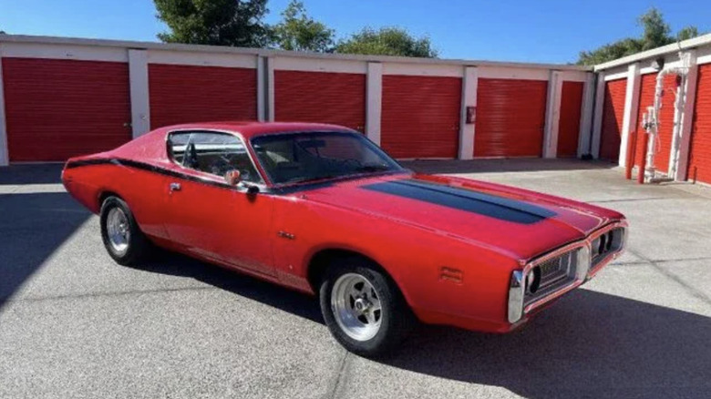 a red and black 1971 Dodge Charger parked in the sun in a storage unit parking lot