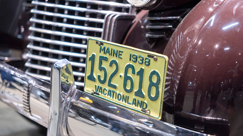 Vilnius Lithuania 2025-04-05 Close-up of a vintage 1938 Maine "Vacationland" license plate mounted on a classic maroon car with chrome bumper and detailed front grille.