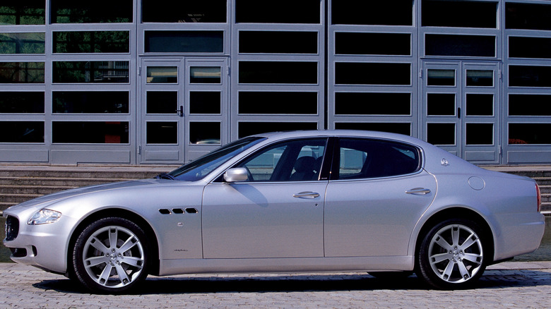 A silver 2003 Maserati Quattroporte parked in front of a building
