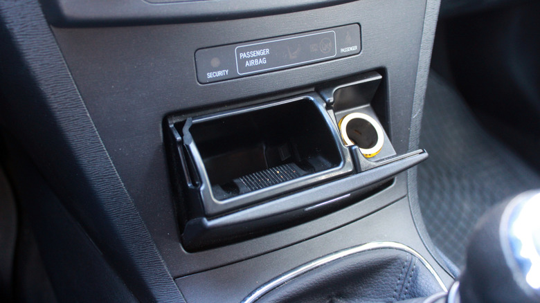 An open ashtray and a lighter socket in the console of a modern car