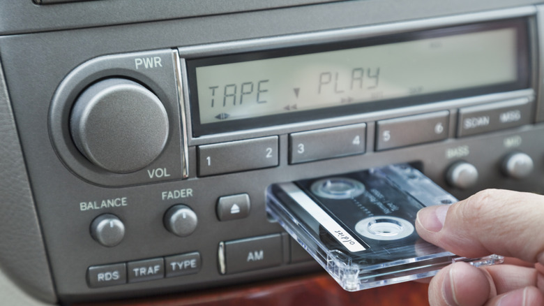 Person inserting cassette tape into player in car