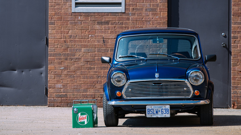 A blue classic Mini Cooper parked outside a brick building