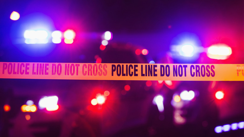 Stock image of police cars with lights on at a crime scene.