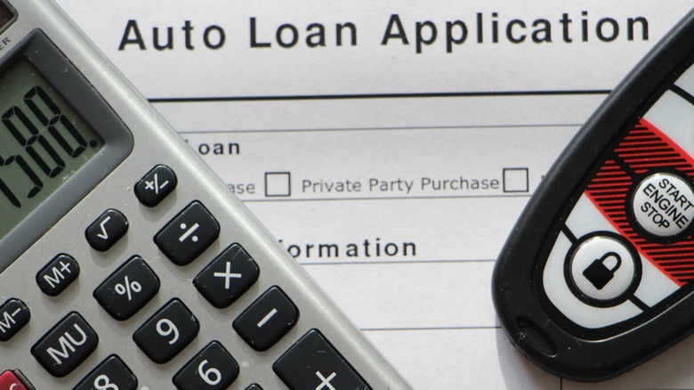 A calculator and car key on a paper car loan application.