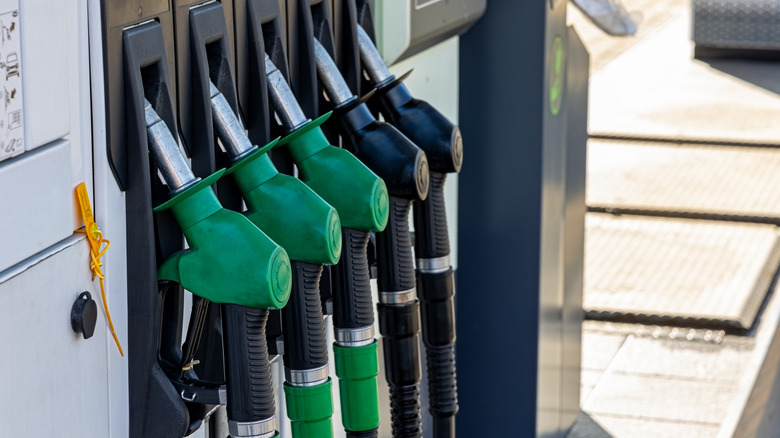 Green and black fuel pump nozzles at a gas station