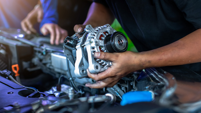 Mechanic holding the alternator of a car