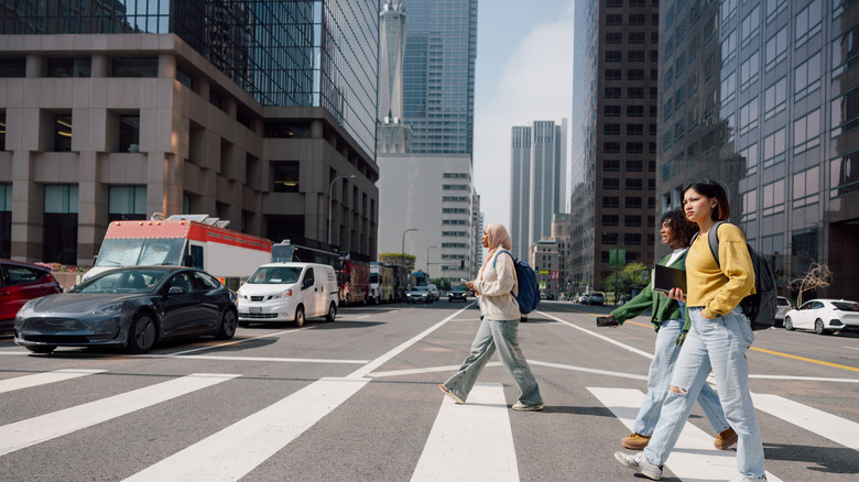 Three pedestrians cross a crosswalk in an urban setting