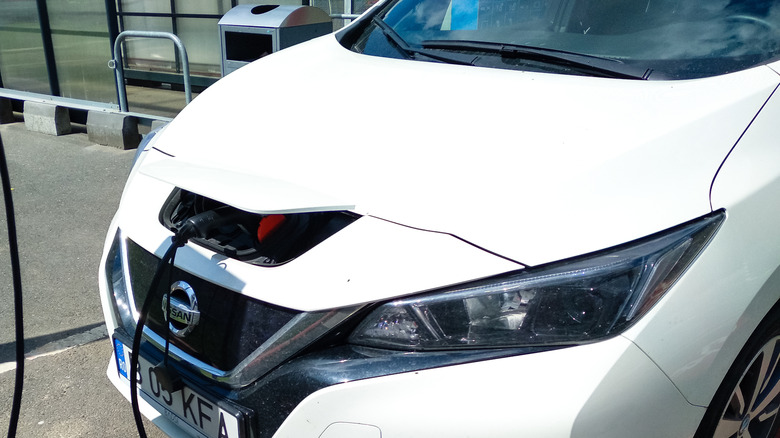 A white Nissan Leaf connected to an EV battery charger
