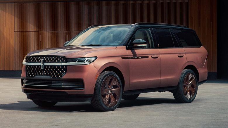front three-quarters shot of Serena Williams' custom Navigator in a bronze color with bronze wheels parked on concrete in front of a wood slatted wall