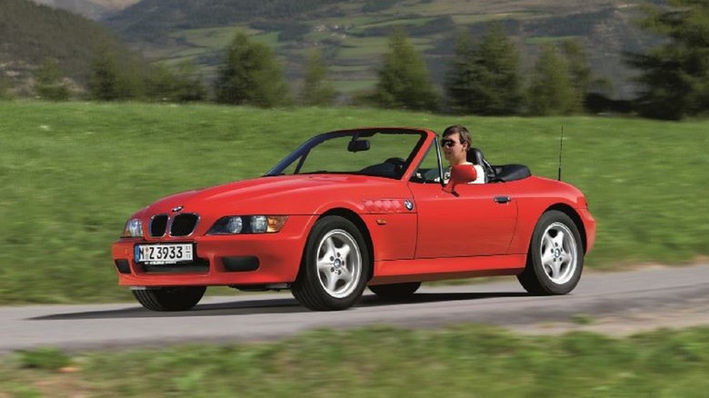 A red BMW Z3 being driven alongside a mountain range.