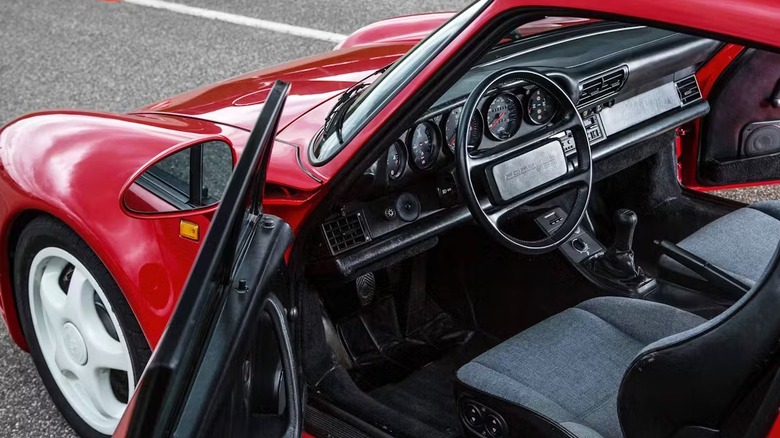 The interior of a red Porsche 959, featuring a manual shifter.