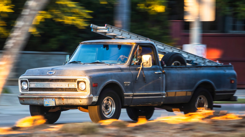 A Chevrolet C20 pickup truck driving while carrying a ladder