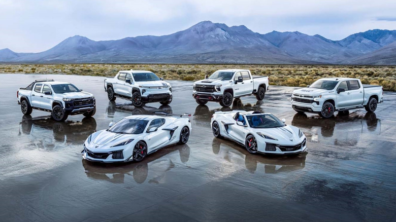 Chevrolet vehicles parked in a formation on a reflective paved surface with mountains in the background