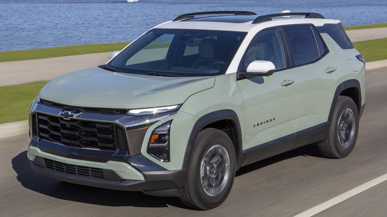Cacti Green 2025 Chevrolet Equinox ACTIV driving on a road next to a body of water