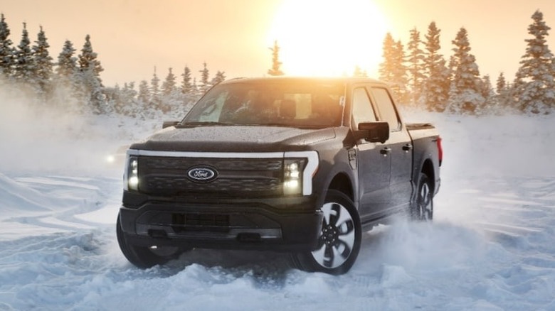 A front shot of a 2023 Ford F-150 Lightning driving in the snow