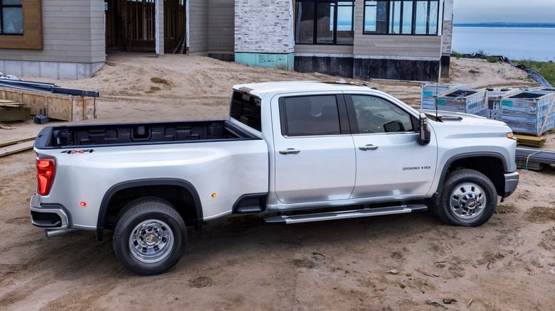 Chevrolet Silverado 3500HD dually pickup truck parked on a sandy surface near a construction site