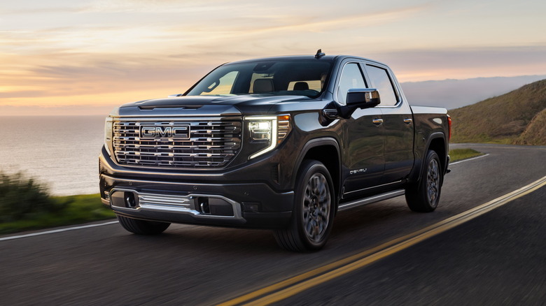 2025 GMC Sierra Denali Ultimate driving on a road along a coastline