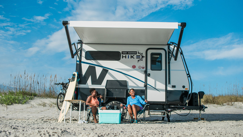Two women enjoying a day at a beach with a Winnebago Hike trailer