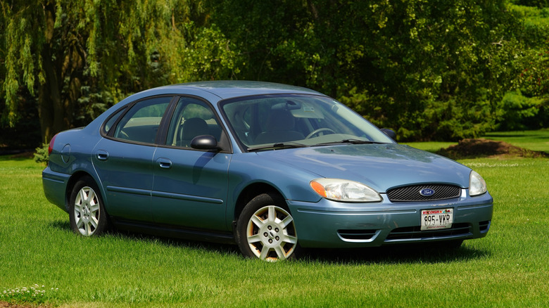 A blue Ford Taurus sedan parked on grass