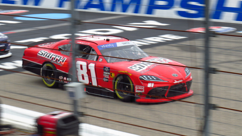 A red 2024 Toyota Supra NASCAR stock car.