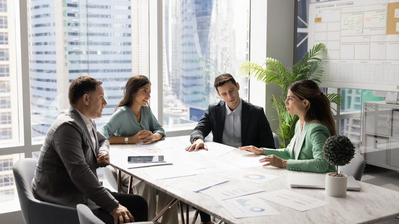 A group of people speaking around a table in an office building