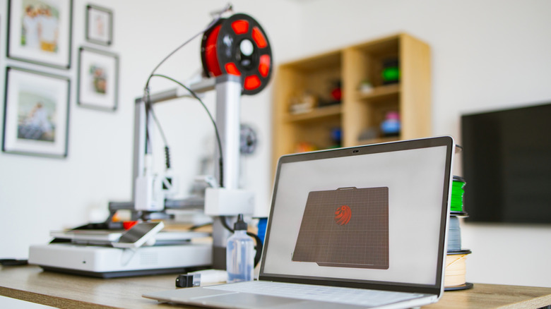 A desktop 3D printer paired with a laptop