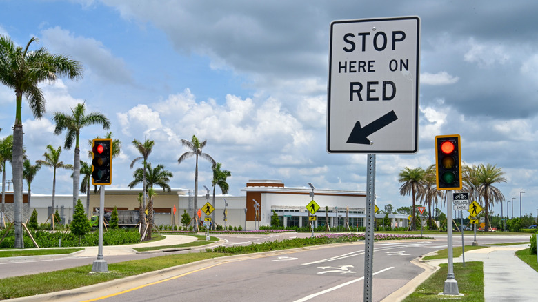 A red light leading up to the roundabout intersection, behind a STOP HERE ON RED sign