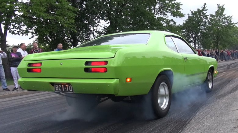 A green 1970 Plymouth Duster does a burnout