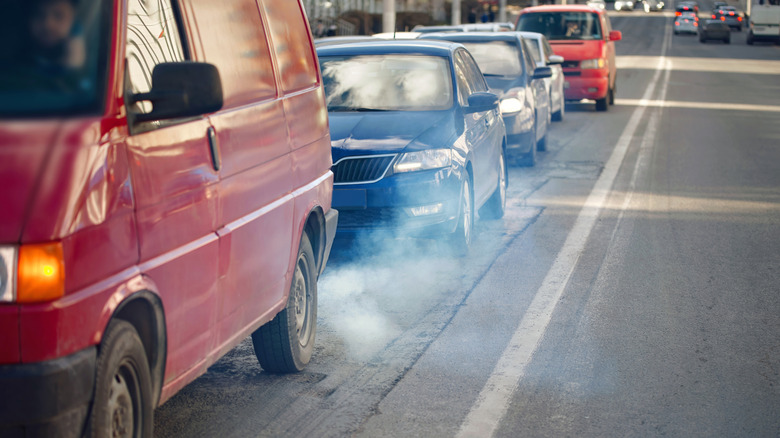 Cars in traffic emitting exhaust.