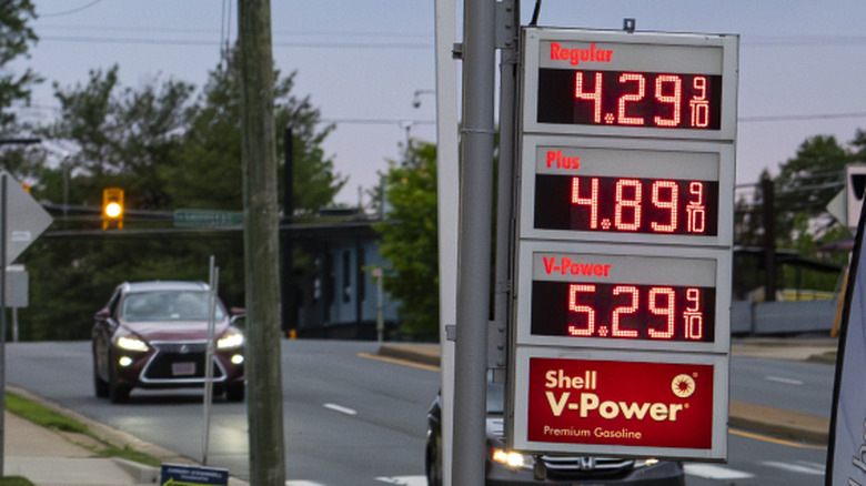 High prices at a gas station as two cars drive by.