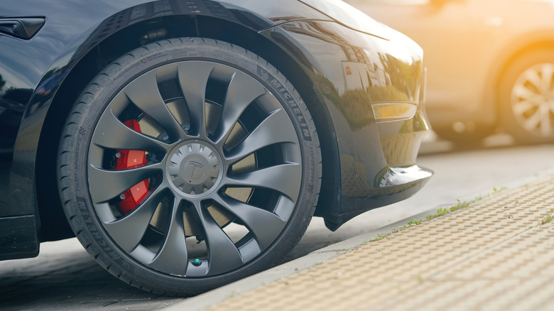 A close-up of a black Tesla EV wearing a Michelin Pilot Sport tire.