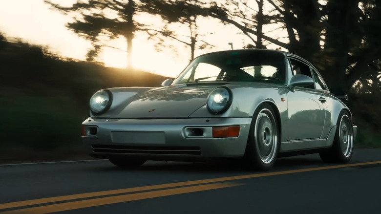 Silver Porsche 964 driving in low light.