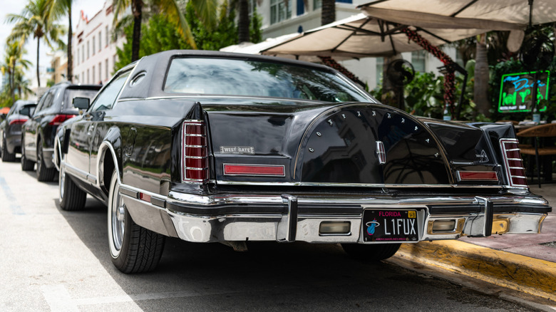 A black Lincoln Continental with a spare tire trunk hump.