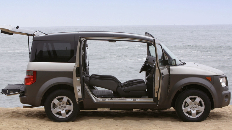 Honda Element with all of its doors open on a beach on a cloudy day