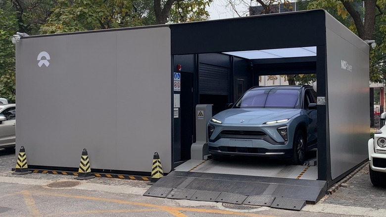 A gray electric car changing its batteries at a battery swapping station