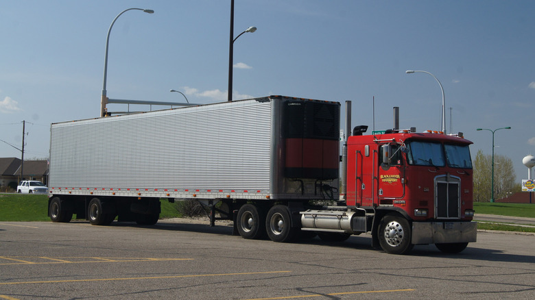A red Kenworth K100 semi truck with a 53-foot trailer.