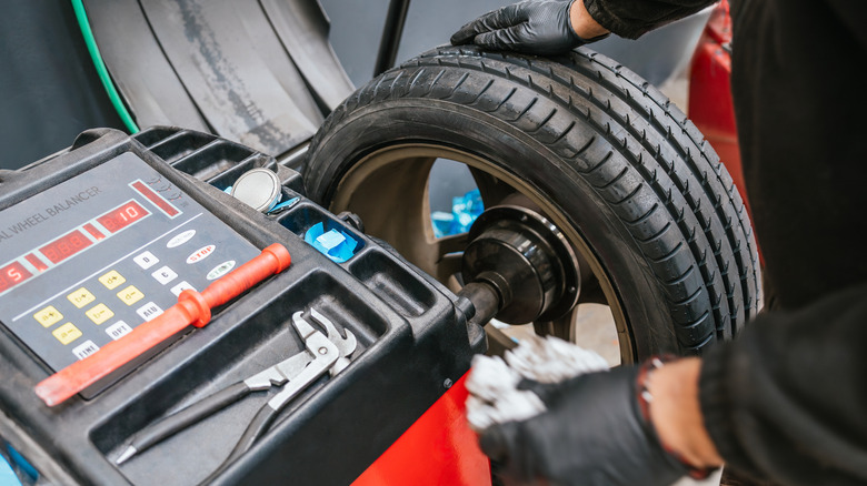 A mechanic using a tire balancer to properly balance a car's tire on its wheel.