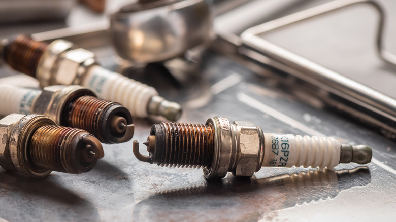 Dirty old spark plugs on a metal tray