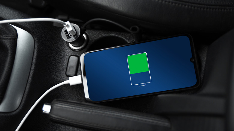 A smartphone plugged into a car's accessory outlet