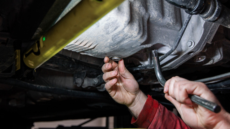Mechanic loosening the oil drain plug to drain the engine oil
