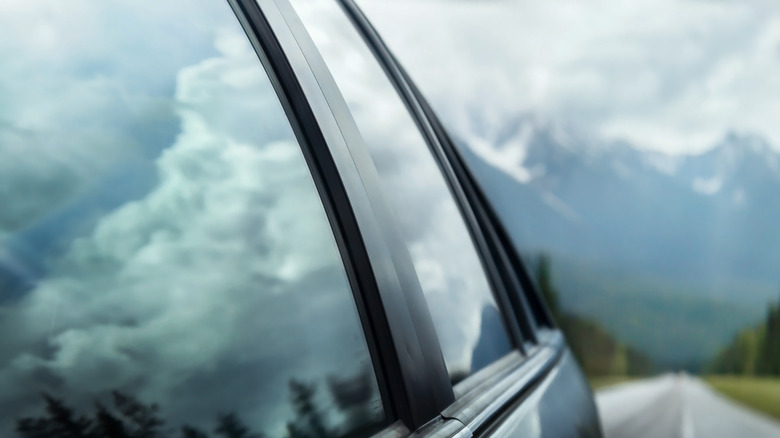 Reflection of nature and skies on a car driving along rural roads.