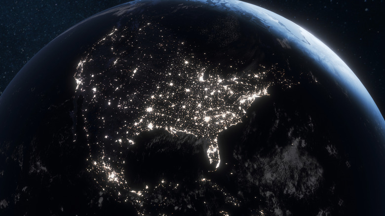 Earth from space at night showing North America illuminated by city lights, highlighting urban areas, human activity, and global connectivity against the dark expanse of the universe